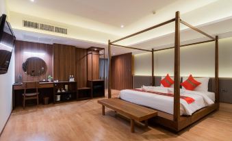 A bed is positioned in the center of the room, accompanied by a wooden table and bench adjacent to it at True Siam Phayathai Hotel
