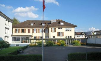 a large , two - story building with a flag flying in front of it , surrounded by trees and grass at Dialoghotel Eckstein