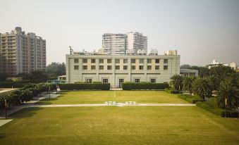 a large building with a green lawn in front of it and tall buildings in the background at DoubleTree by Hilton Agra