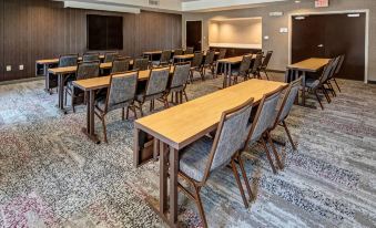 a large conference room with wooden tables and chairs arranged in rows , providing seating for attendees at Courtyard Troy