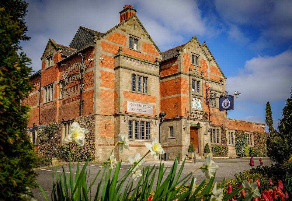 "a large red brick building with a sign that says "" brimpton "" and a garden of flowers in front" at Grosvenor Pulford Hotel & Spa
