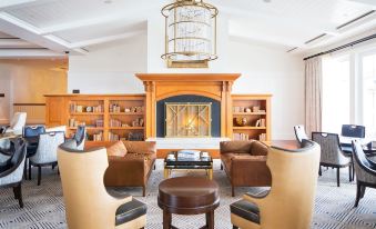 a living room with a fireplace and bookshelves , featuring a group of brown leather chairs at Montage Laguna Beach