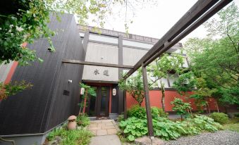 a modern building with a large wooden door and a brick walkway leading up to it at Oyado Mokuren
