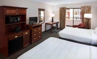 a hotel room with two beds , a desk , and a tv , all situated near a window at Grand Hotel