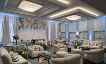 a large , well - decorated living room with multiple couches and chairs arranged for a formal event at Hilton Los Angeles-Culver City, CA