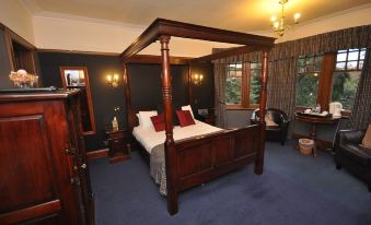 a large bed with a wooden frame and white linens is in a room with blue carpeting at Rivendell
