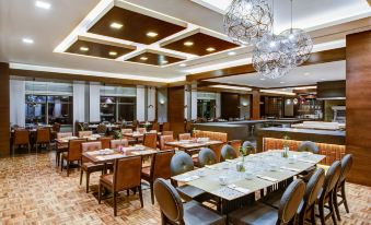 a modern restaurant with wooden floors , white walls , and multiple dining tables set for guests at Sheraton Grand Samsun Hotel