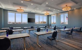a conference room with rows of tables and chairs , a large screen on the wall , and a flag hanging from the ceiling at Fenwick Shores, Tapestry Collection by Hilton