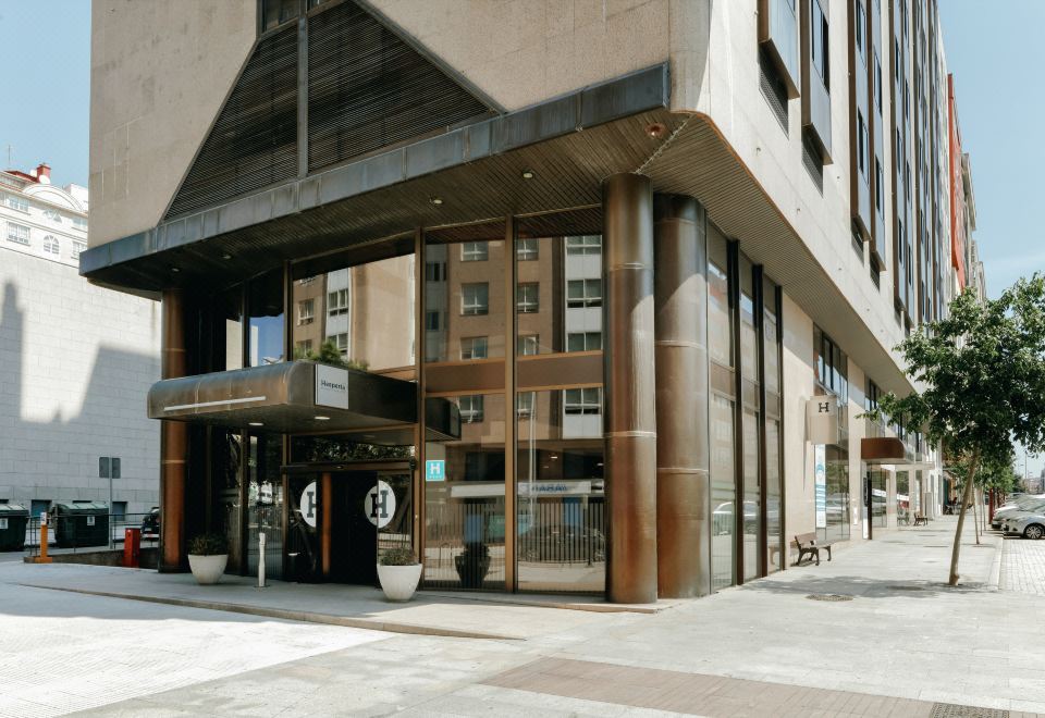 a modern building with large windows and a black sign , located on a city street at Hesperia Vigo