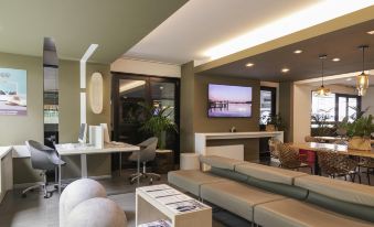 a modern living room with a large flat screen tv mounted on the wall , along with several chairs and couches at Mercure Milano Agrate Brianza