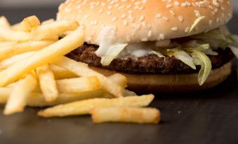 a burger with cheese and lettuce is sitting on a plate next to a pile of french fries at Hotel Lavender Senawang