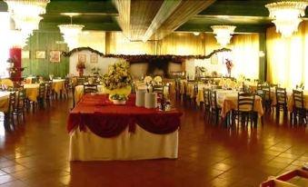 a large dining room with multiple tables covered in red tablecloths , decorated with flowers and candles , creating a festive atmosphere at Hotel Antares