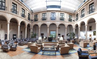 a large , open atrium with a series of arches and a round room filled with couches and chairs at Parador de Lerma