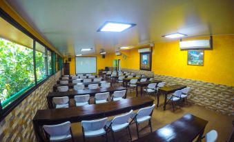 a large , empty conference room with rows of white chairs and wooden tables , set against yellow walls at Hotel Estero y Mar
