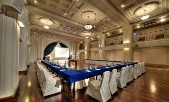 a large conference room with blue tablecloths and chairs , a projector screen at the front at The Phoenicia Malta