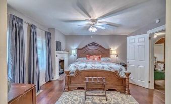 a large bedroom with hardwood floors , a king - sized bed , and a fireplace in the corner at Elmrock Inn