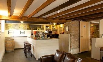a cozy living room with wooden beams , a leather couch , and a bar area with various appliances at The Anchor Inn