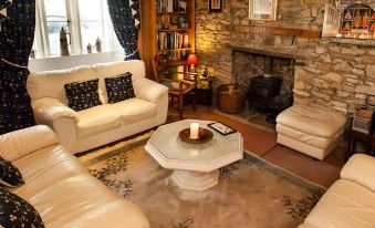 a cozy living room with a fireplace , several couches and chairs , and a television at Ashfield House