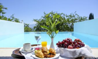 There is a table next to the swimming pool at a resort where food and drinks are available at Ionian Blue Bungalows and Spa Resort