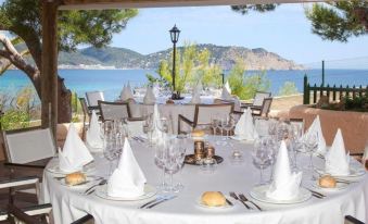 a beautifully set dining table with white tablecloths , wine glasses , and silverware , set for a meal at Invisa Hotel Club Cala Blanca