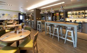 a modern restaurant with wooden tables , chairs , and bar stools , as well as a wine bar at Premier Inn Felixstowe Town Centre