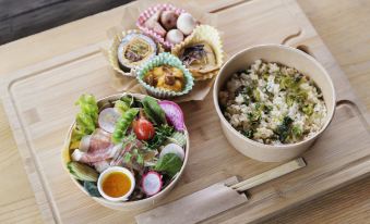 a wooden cutting board with two bowls of food , one containing salad and the other filled with rice at Fairfield by Marriott Tochigi Utsunomiya