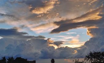 a beautiful sunset over the ocean , with a cloudy sky and fluffy clouds in the background at Cal Music B&B