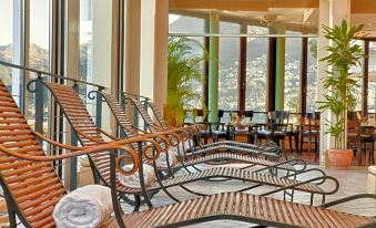 a large room with multiple lounge chairs arranged in front of a large window , providing a view of the city at Suitenhotel Parco Paradiso