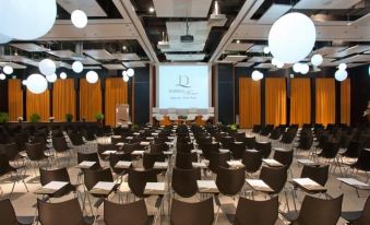 a large conference room with rows of chairs arranged in a semicircle , and a projector screen mounted on the wall at Domina Zagarella Sicily
