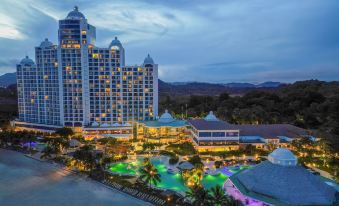 a large hotel with a swimming pool in front of it , surrounded by palm trees and mountains at The Westin Playa Bonita Panama