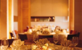 A table is set for dinner in a dining room with large windows and wood paneling at Rambler Oasis Hotel