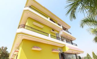 a yellow and white building with balconies , located in a tropical setting with palm trees at Collection O 27949 Hotel Kriti Green