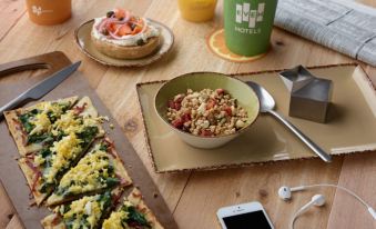 a wooden table with a variety of food and drinks , including pizza , bread , and a cup of tea at Even Hotel Rockville - Washington DC Area
