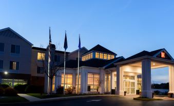 a large hotel building with multiple flags flying outside , creating a welcoming atmosphere for guests at Hilton Garden Inn Kennett Square