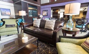 a modern living room with a brown leather couch , coffee table , and various decorative items at Drury Inn & Suites Atlanta Morrow