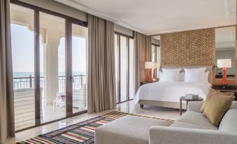 a spacious bedroom with a large bed and a view of the ocean through a glass door at Four Seasons Hotel Tunis