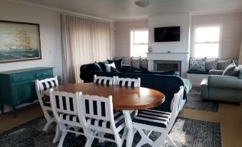 a dining room with a table surrounded by white and black striped chairs , located next to a living area at South Point Guest Lodge
