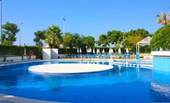 a large outdoor swimming pool surrounded by lounge chairs and umbrellas , providing a relaxing atmosphere at Royal Beach