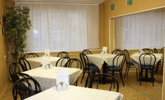 a dining room with several tables and chairs , some of which have white tablecloths and napkins at Norilsk