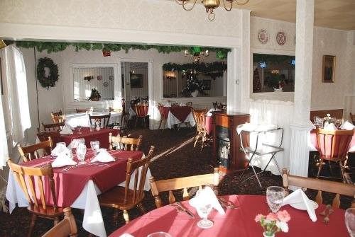 a well - decorated restaurant with multiple dining tables , each set with white tablecloths and napkins , ready for guests at Christman's Windham House