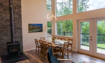 a modern dining room with large windows , wooden floors , and a dining table surrounded by chairs at Woodland Cabins