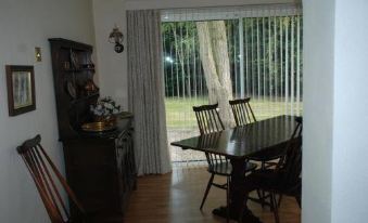 a dining room with a wooden table and chairs , a large window , and a book on the table at Greenhollow