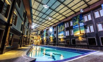 an indoor swimming pool with a mural on the wall , surrounded by glass windows and balconies at Crown Victoria Hotel Tulungagung