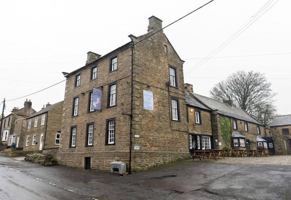 a large stone building with a curved front , situated in a parking lot near a river at The Ancient Unicorn