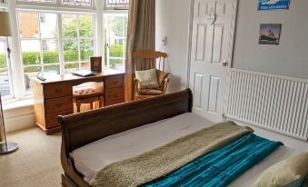 a cozy bedroom with a wooden bed , a desk , and a door leading to a balcony at The Bugle Coaching Inn