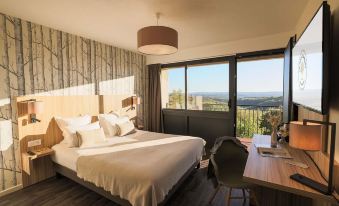 a modern hotel room with large windows offering a view of the landscape , a bed , and a desk at Le Bois d'Imbert