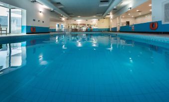 an empty indoor swimming pool with blue tiles and a few people inside the pool at The Inn at Dromoland