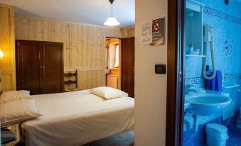 a small room with a bed , wooden walls , and a door leading to another room at Santa San