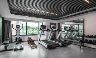 A spacious room with multiple treadmills and other exercise machines is located in front of the window at Country Inn