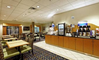 a breakfast area in a hotel , featuring a dining table and chairs , a counter with a coffee maker , and a microwave at Country Inn & Suites by Radisson, Evansville, IN